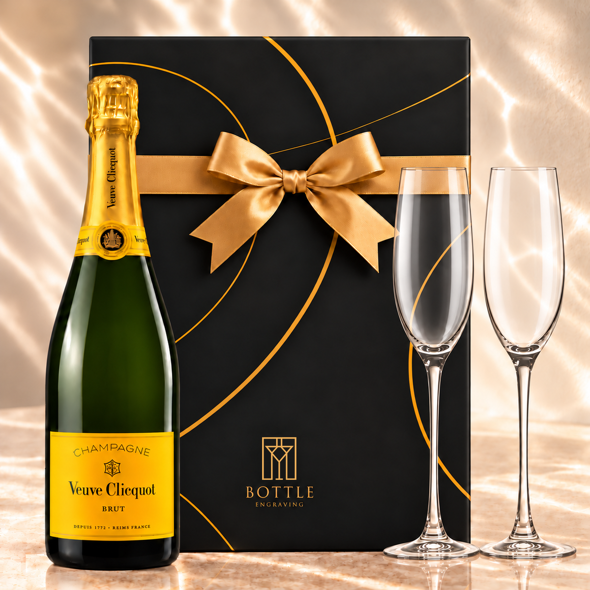 Veuve Clicquot Brut Champagne gift set with two champagne flutes and a black Bottle Engraving gift box tied with a gold bow.